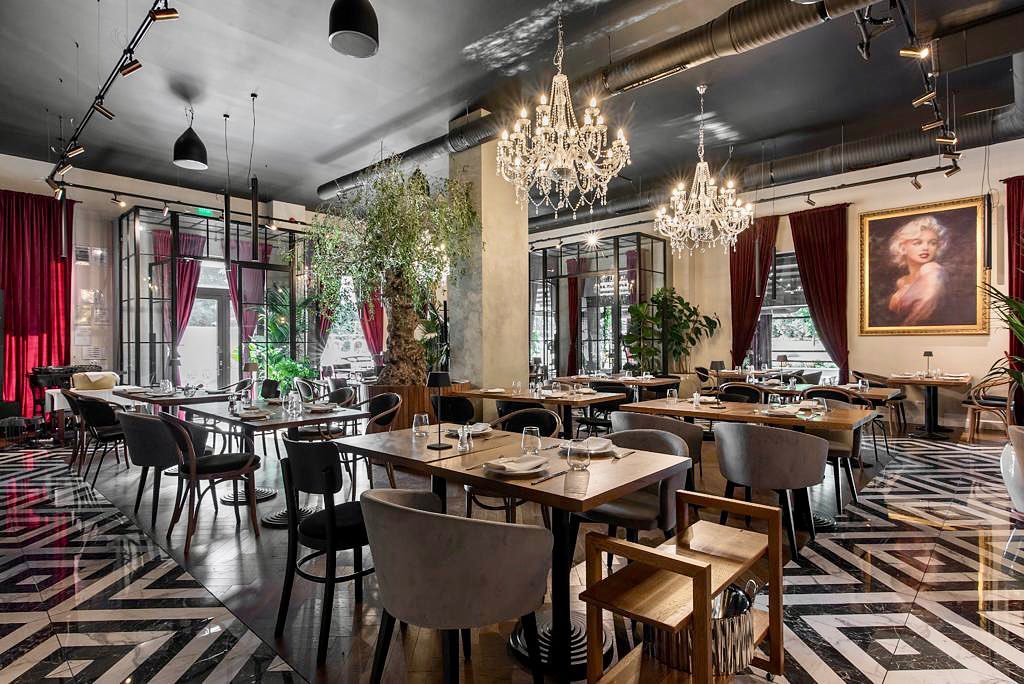 restaurant elegant, cu candelabru luxos, podea cu mozaic alb negru, mobilier clasic si tablouri pe pereti la Oliveto, restaurante Pipera