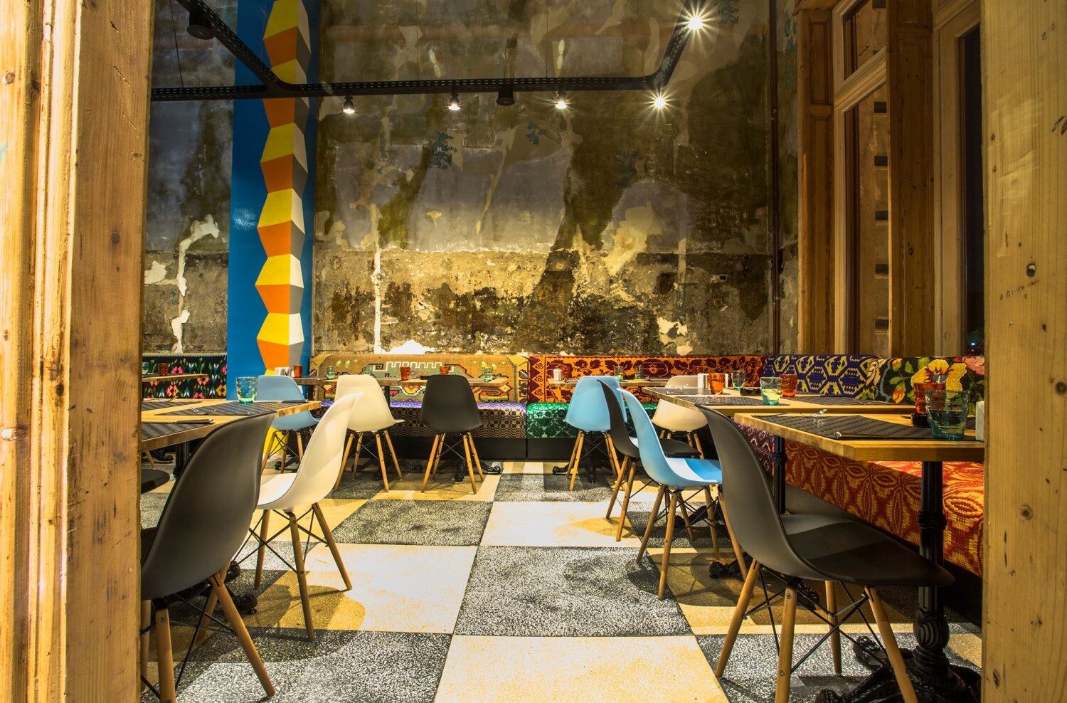 sala de mese la Restaurant Mahala, cu coloane pictate cu coloana infiniturlui, scaune moderne si bancute acoperite cu stergar etraditionale, iar peretii netencuiti, unul din Restaurante din Bucureşti de recomandat unui turist
