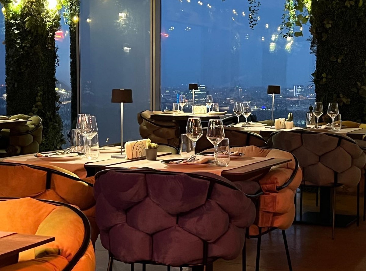 mese iluminate discret in restaurantul 18 Lounge, fotografiat seara, prin ferestrele caruia se vede orasul de sus