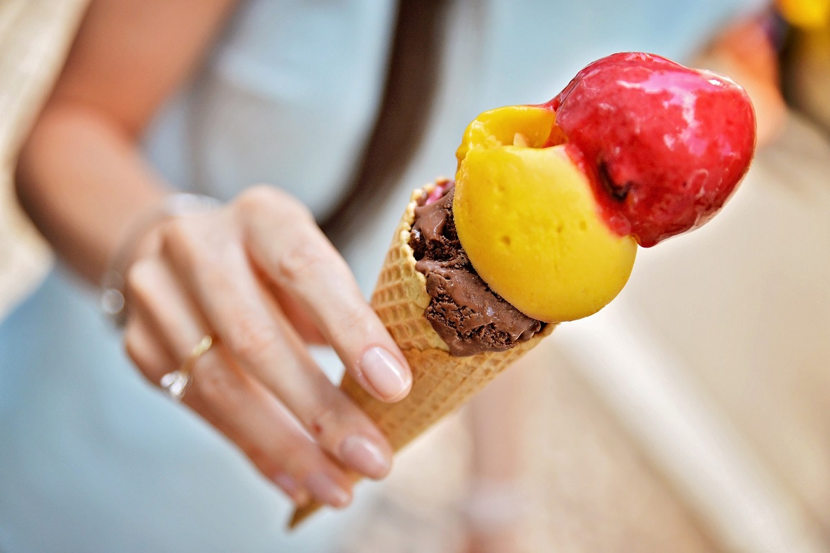 prim plan cu mana unei fete care tine un cornet cu 3 cupe de înghețată, de ciocolată,vanilie și căpșuni,la Zexe Braserie din București