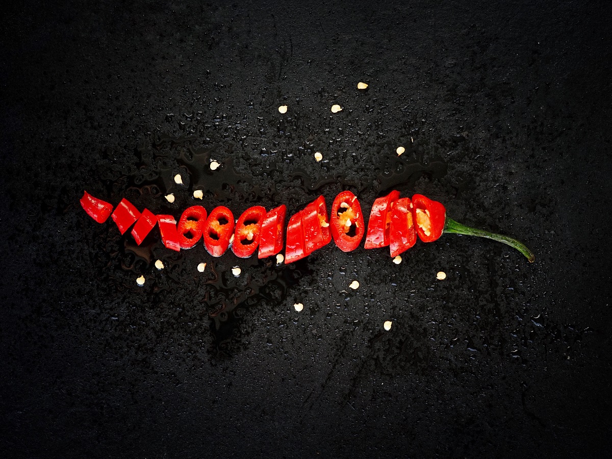 ardei iute roșu tocat rondele, cu semințe împrăștiate, fotografiat pe fundal negru, folosit la mâncarea picantă