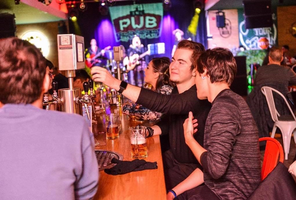 oameni la bar turnandu-si bere in pahare, la The Pub Universității