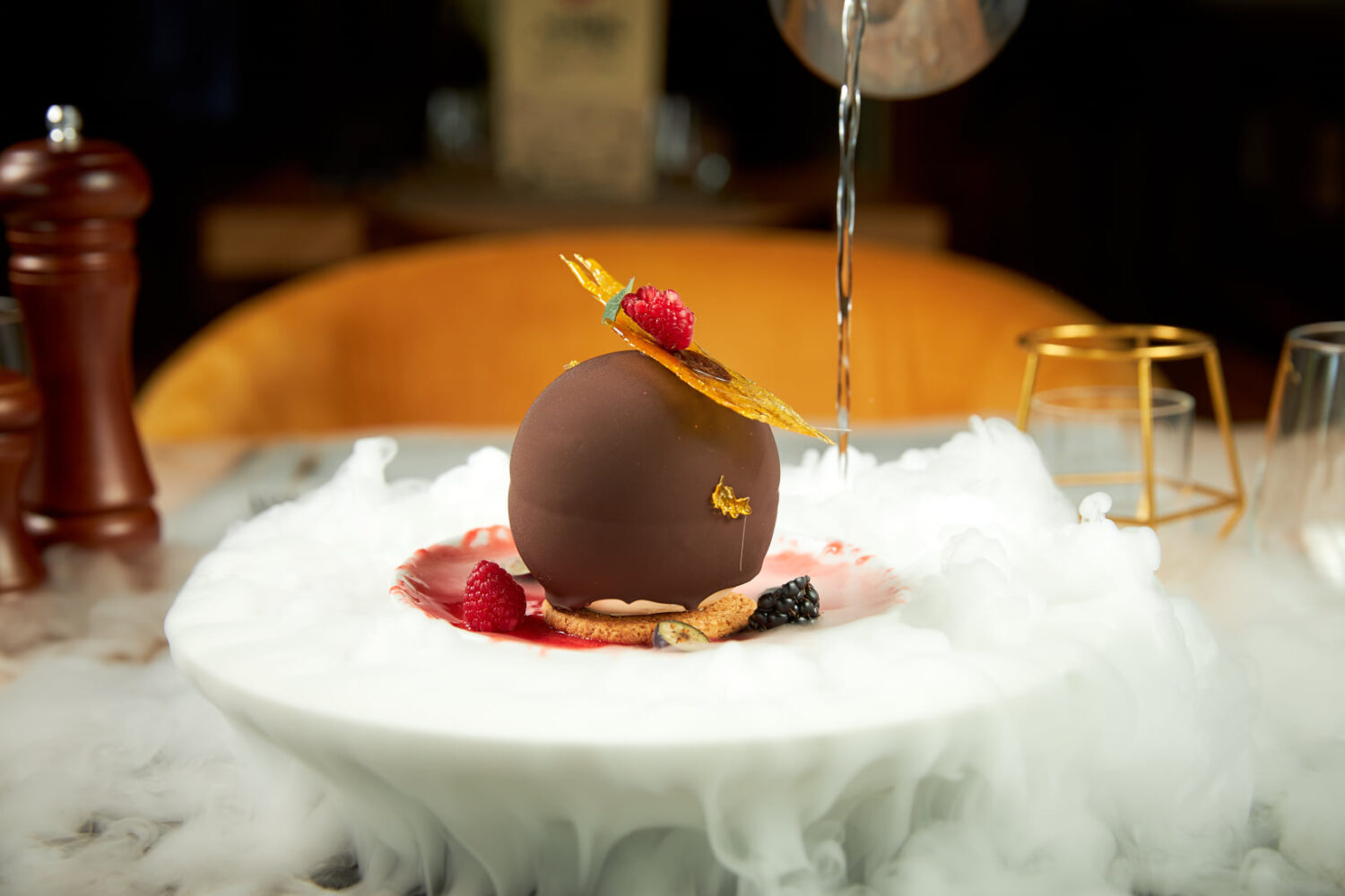 Glob de ciocolată umplut cu cremă de mascarpone și vișine, servit pe gheață carbonică la restaurant The Mark