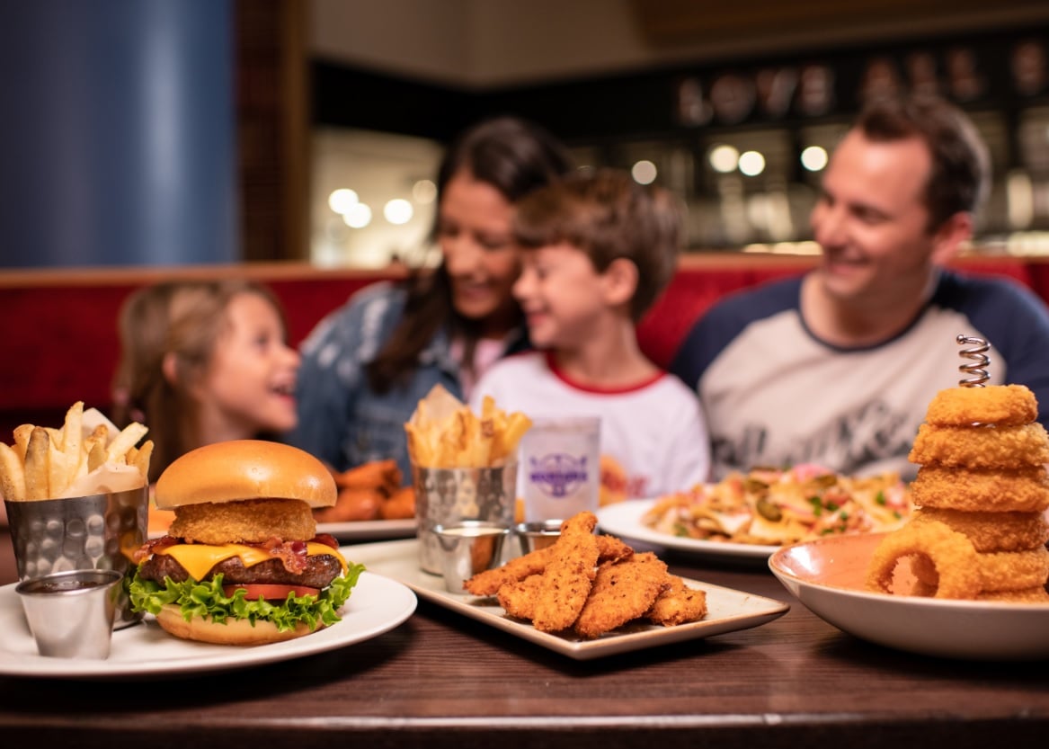 familie luand masa in fundal si in prim plan hamburgeri de la hard rock cafe, recomandări de weekend pranz gratuit pentru copii