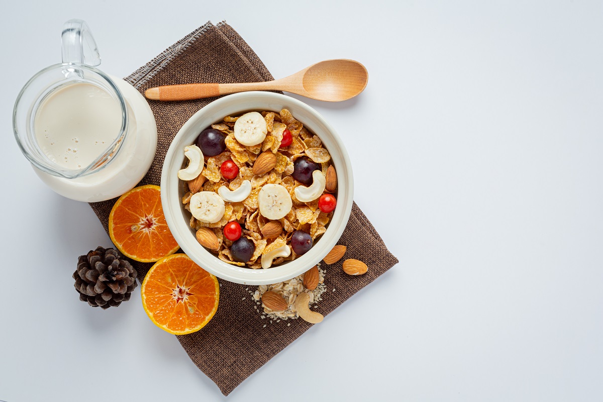 Bol cu cereale si mix de fructe fotografiat pe fundal gri, cu granola, unul din alimente sănătoase care conțin zahăr