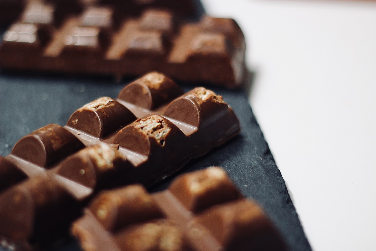 close up cu 3 batoane de ciocolata asezate pe o carpa neagra