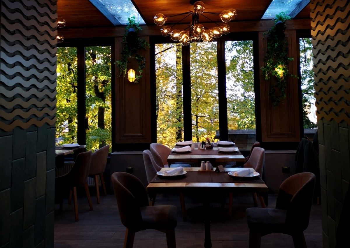 imagine din restaurant Sub Tâmpa din Brașov, amenajat elegant, cu ferestre mari prin care se vad copacii