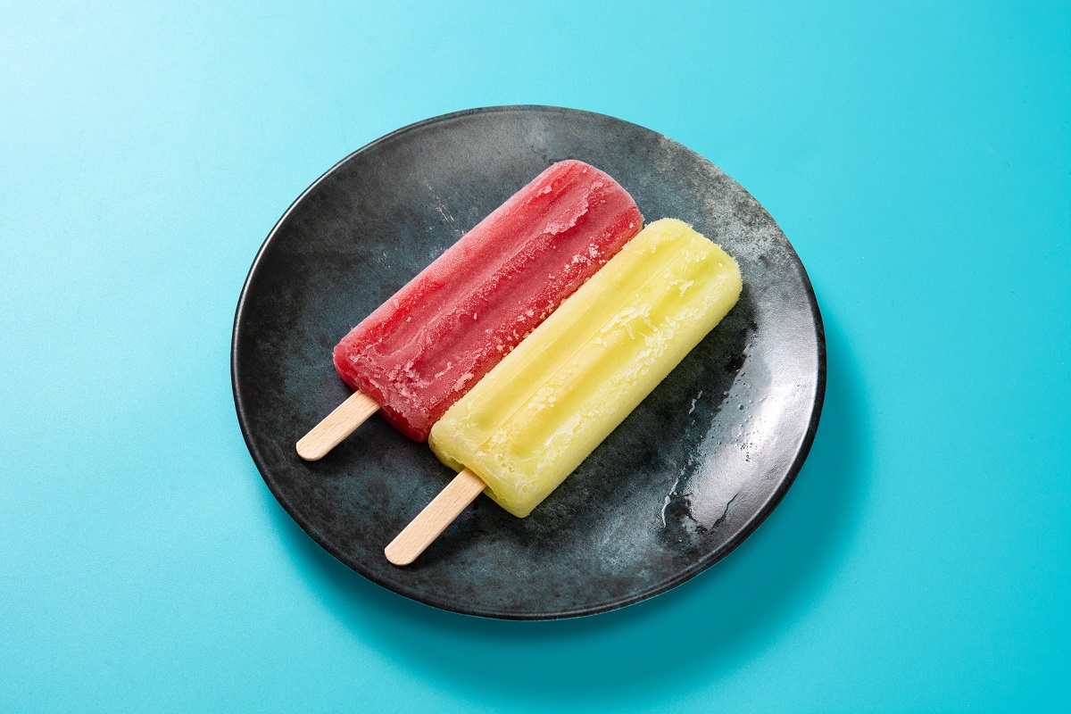 Strawberry and lemon popsicles on blue background.