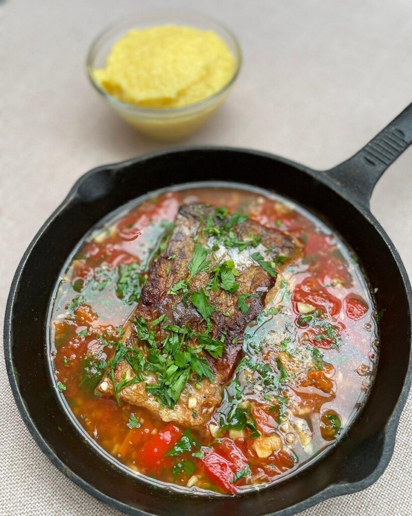 tigaie metalica in care a fost preparata plăchie din pește in sos rosu, cu legume și verdeață - gustul copilăriei