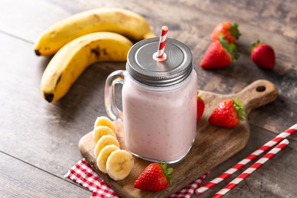 Fresh strawberry and banana smoothie in jar on wooden table