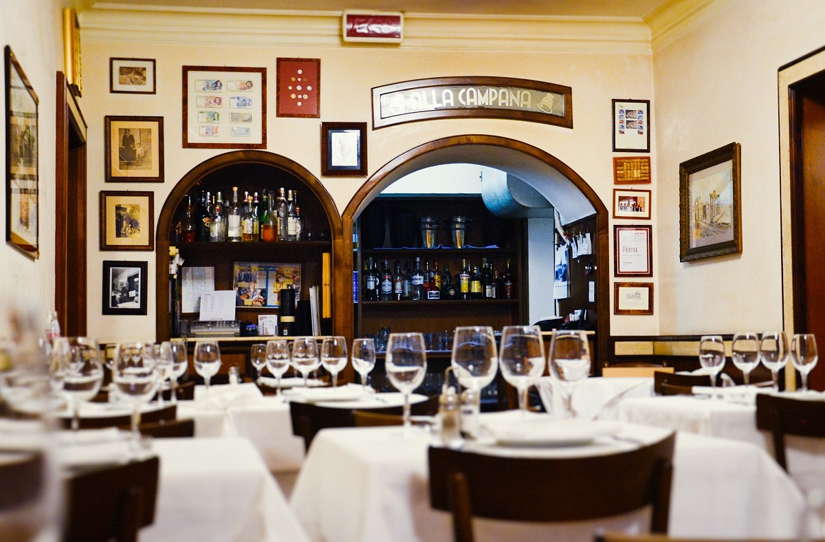 imagine din restaurant La Campana, cu mese cu fete de masa alba si in fundal pereti cu bolta prin care se vede barul, unul dintre cele mai bune restaurante de la Roma