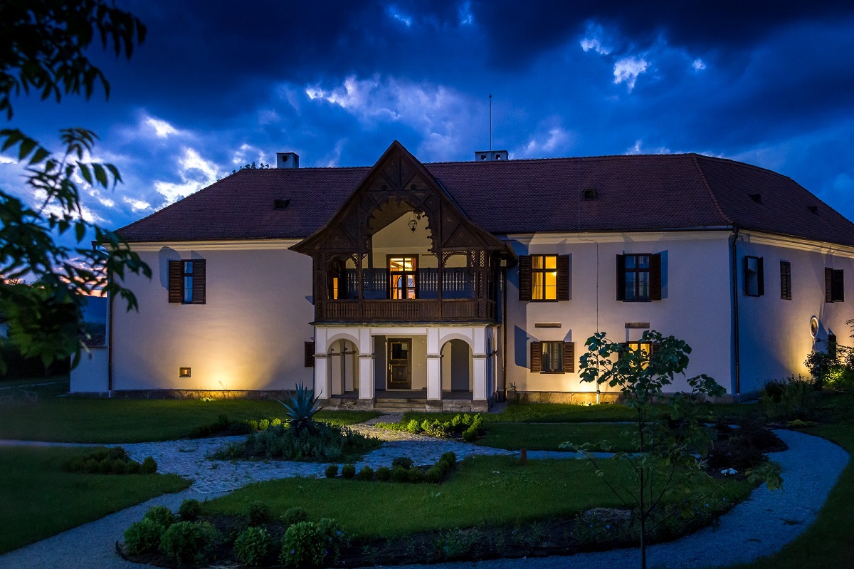 Castelul Daniel fotografiat seara, luminat exterior si cu lumini aprinse la ferestre, unul din conace din România pe care să le vizitezi