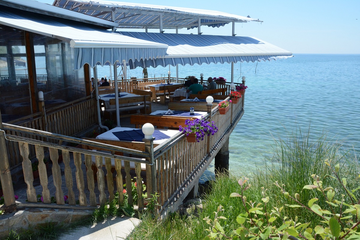 mese asezata pe terasa restaurantului Dalbokam acoperita cu copertine de soare si marea in fundal