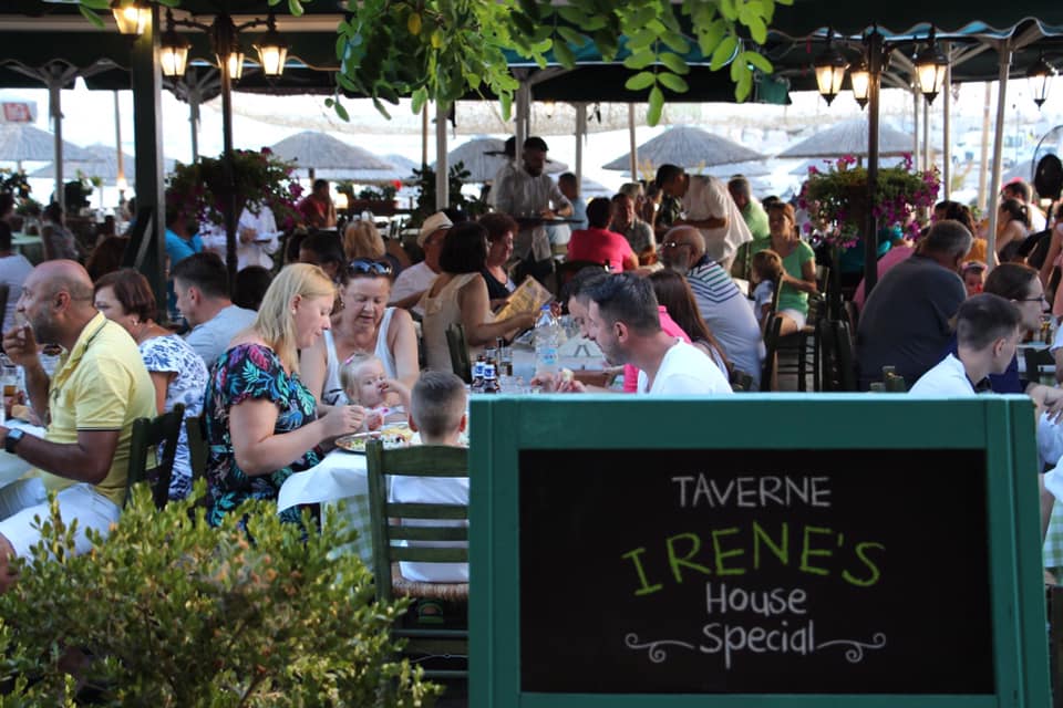 Taverna Irene, una din taverne și restaurante bune din Thassos, cu mesele pline de oameni si un afis la intrare cu specialitatea casei