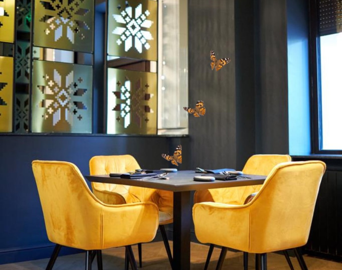 masa de la restaurant Grai, cu 4 scaune tapitate, aurii, in dreptul unei oglinzii sablate cu modele traditionale romanesti in forma de fulg de nea