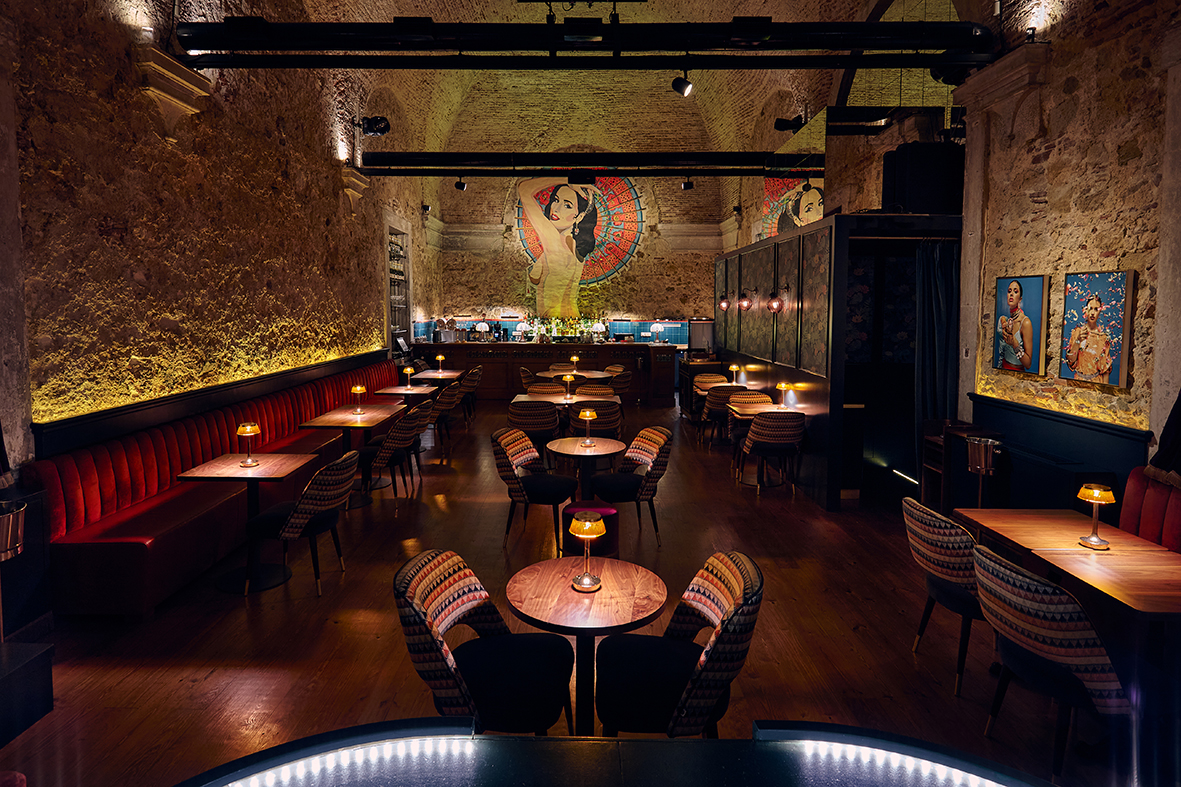 sala de mese de la Mini Bar, iluminat discret, cu canapele de piele si un perete mural in fundal, foarte elefgant, una din destinații culinare din Lisabona