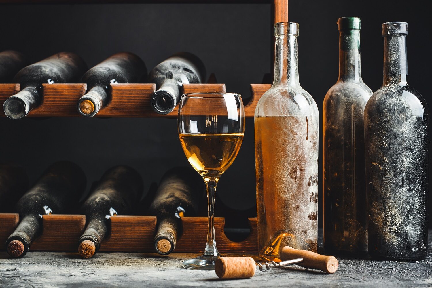 sticle și pahar de vin așezate pe o masă într-o cramă, reprezentativ pentru accesorii pentru vin
