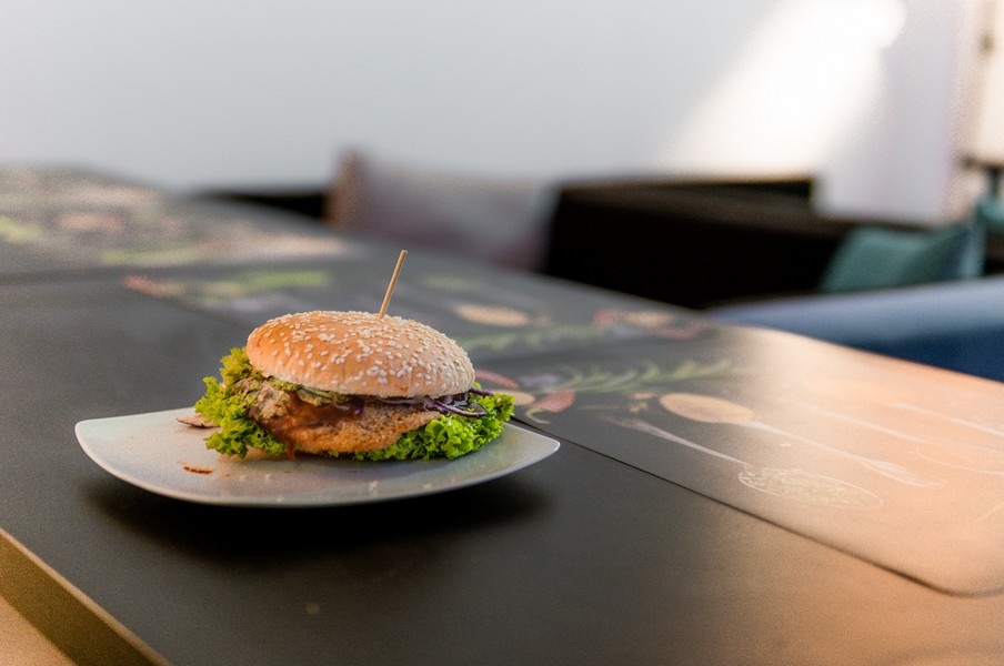 closeup cu un burger vegan asezat pe o farfurie pe o masa din restaurant Level Up, unul din restaurante vegetariene București