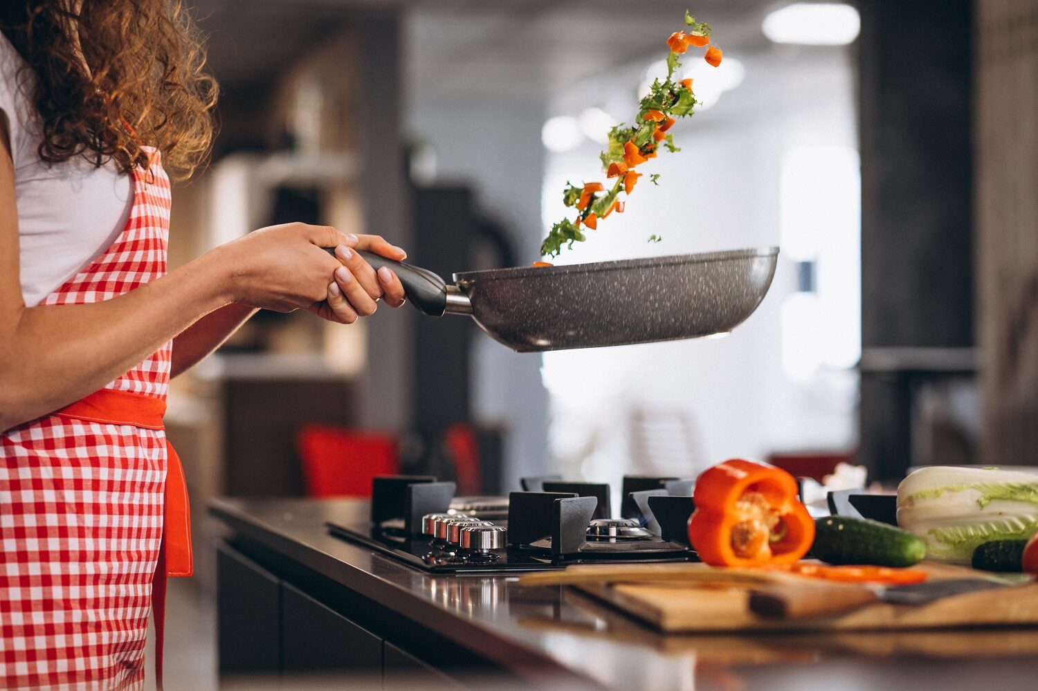 Bucatareasa care gateste legume la tigaie, imagine reprezentativă pentru ce greșești când gătești