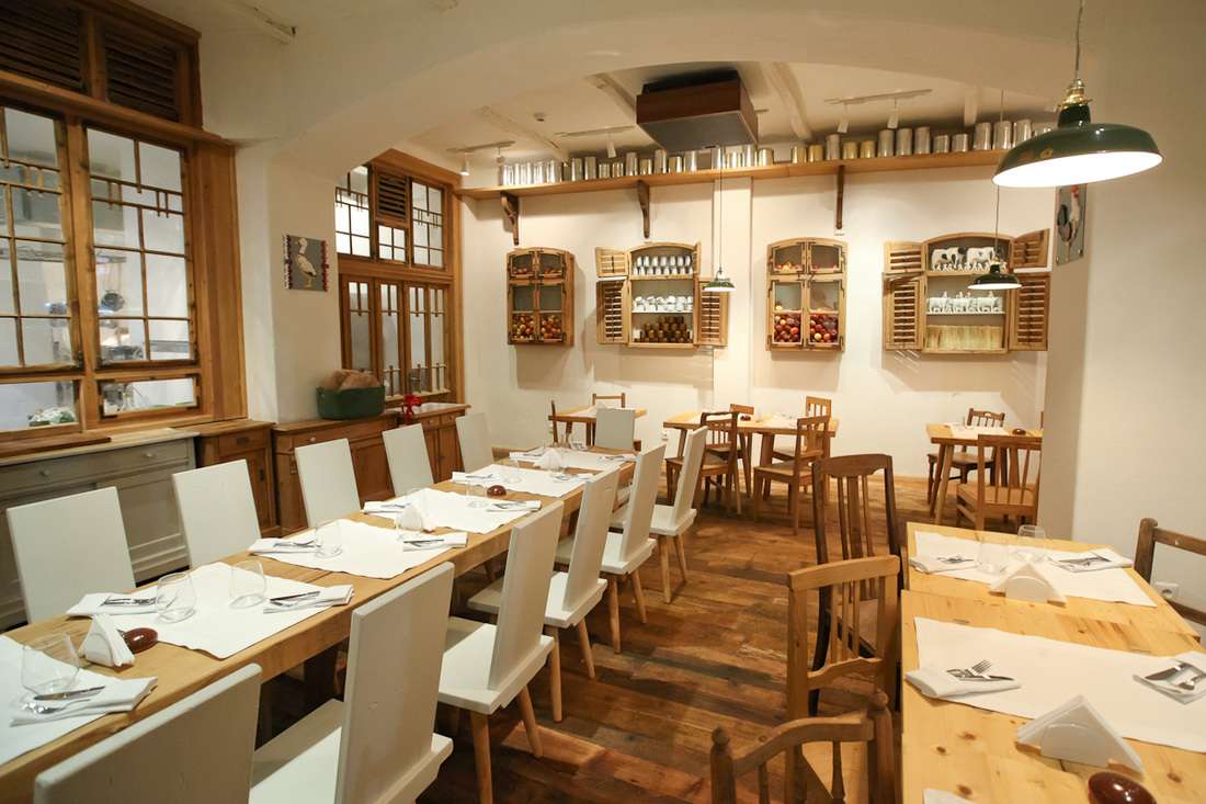 Restaurant Lacrimi și Sfinți, cu o masa lunga intinsa pe mijloc, iar peretii decorati cu rafturi care au obloane
