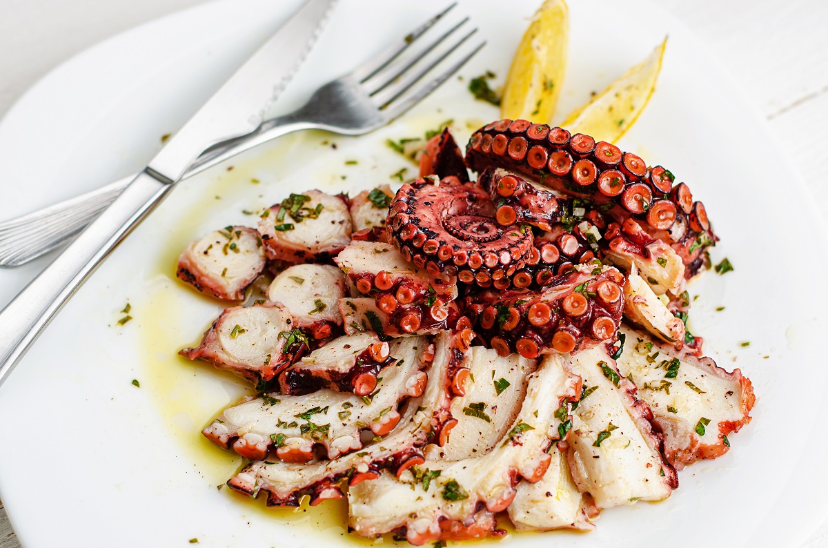 Delicious octopus carpaccio with dressing on white plate. Seafood delicacy