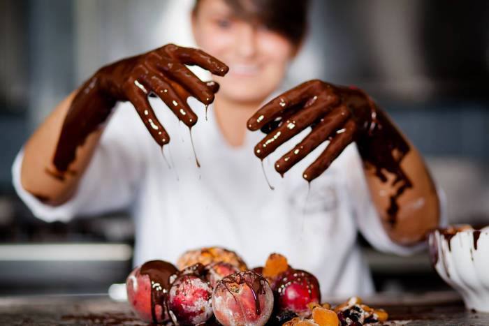 Imagine blurata cu Ana Consulea si prim plan pe mainile ei pline de ciocolata, in timp ce prepara prajituri