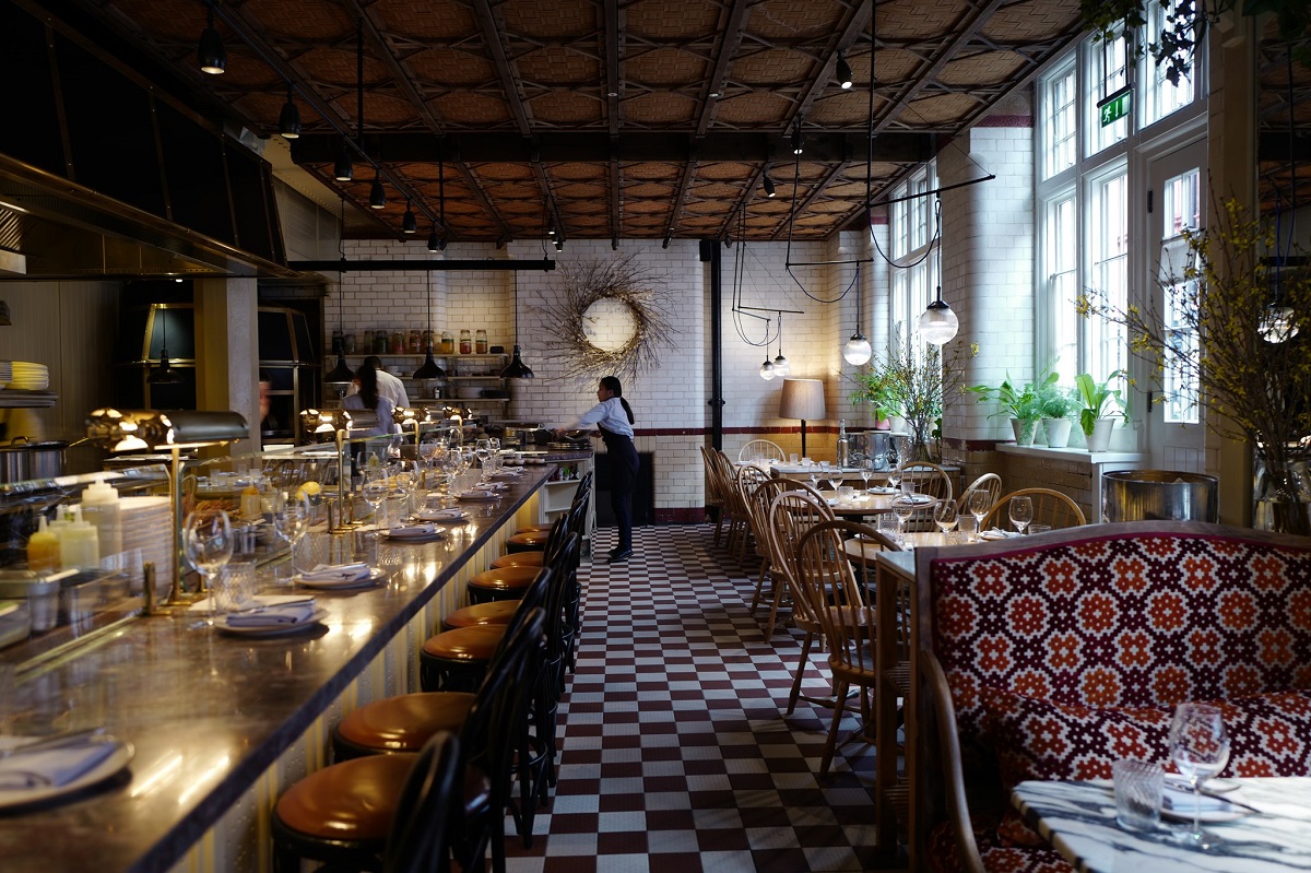 interiorul din restaurant Chiltren Firehouse, cu bar masiv pe stanga si mese pe dreapta, in fata unor geamuri mari, decorat modern