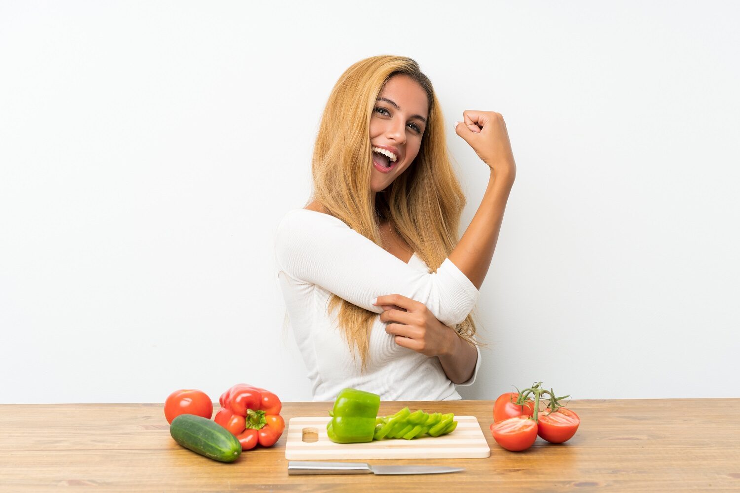 Young blonde woman with vegetables in a table making strong gesture - imagine reprezentativă pentru alimente care întăresc imunitatea
