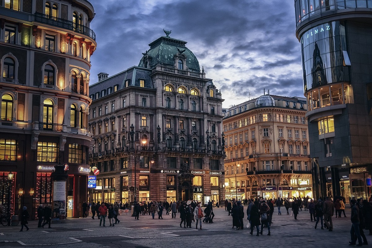 Viena, fotografiata seara, cu cladiri istorice cu lumini aprinse si oameni pe strada