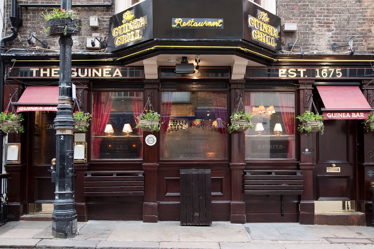 Restaurant Guinea Grill, cu aspect clasic, cu vitrine din lemn inchis la culoare si firma scrisa cu auriu, restaunrant und emâncăm în Londra