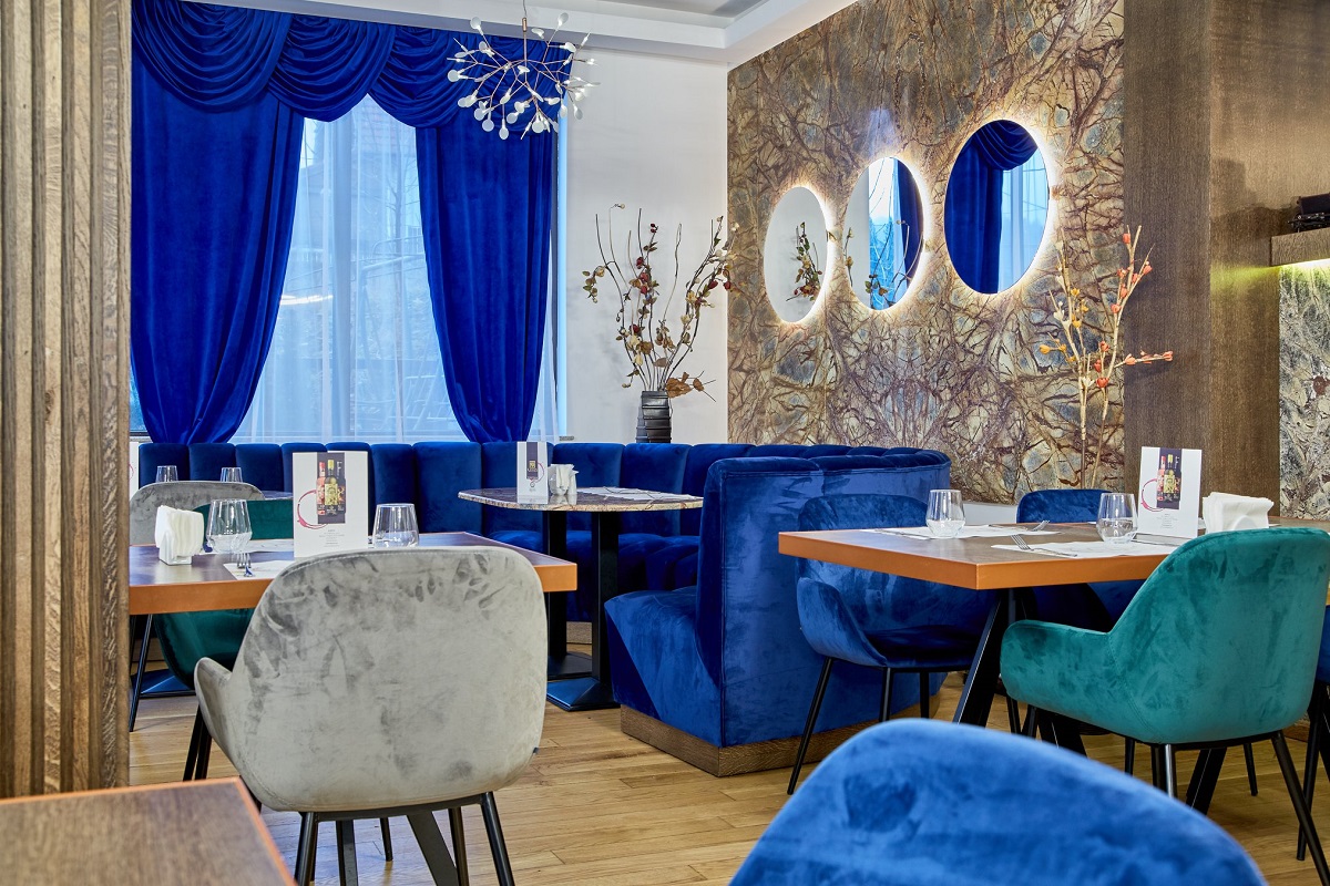 restaurant Kayus din Bușteni, cu scuane tapitate, gri, canapele din catifea albastra, 3 oglinzi pe perete, cu draperii de catifea albastre. Unul dintre cele mai bune restaurante de pe Valea Prahovei