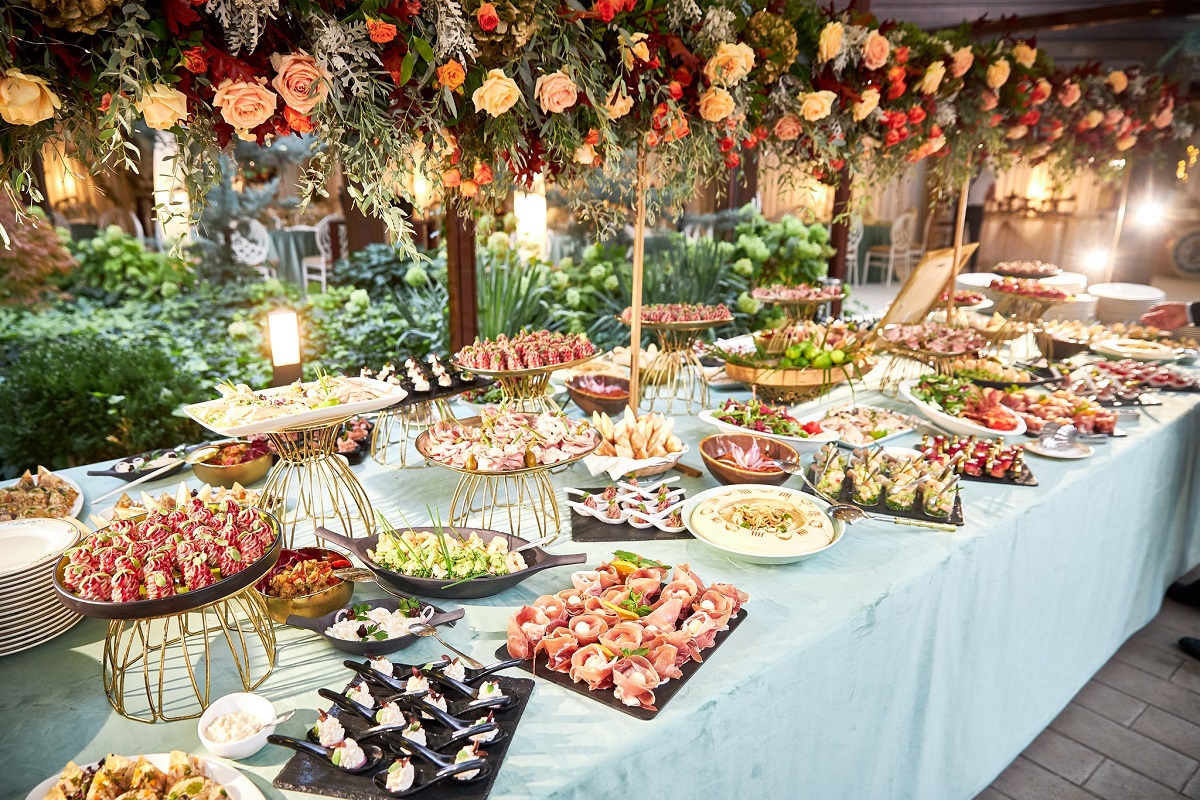 masa festiva cu multe platouri de mancare, decorata frumos, cu flori ornamentale atarnand desupra la aniversarea Restaurant Casa Doina