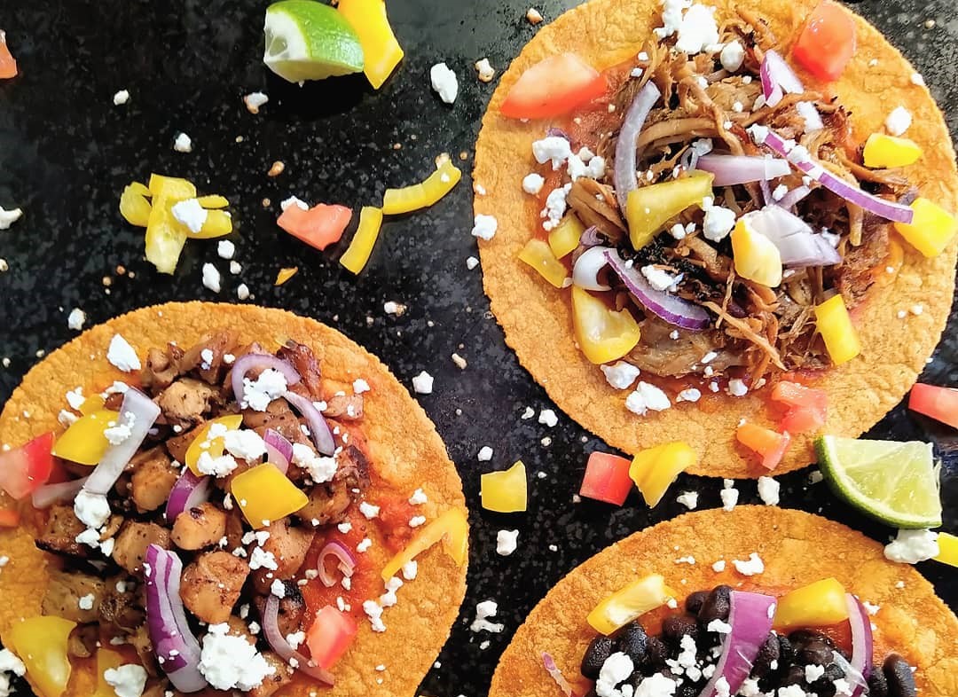 3 tacos fotografiate pe fundal negru, cu ceapa, ardei gras, rosii si carne de porc la Maya Fresh