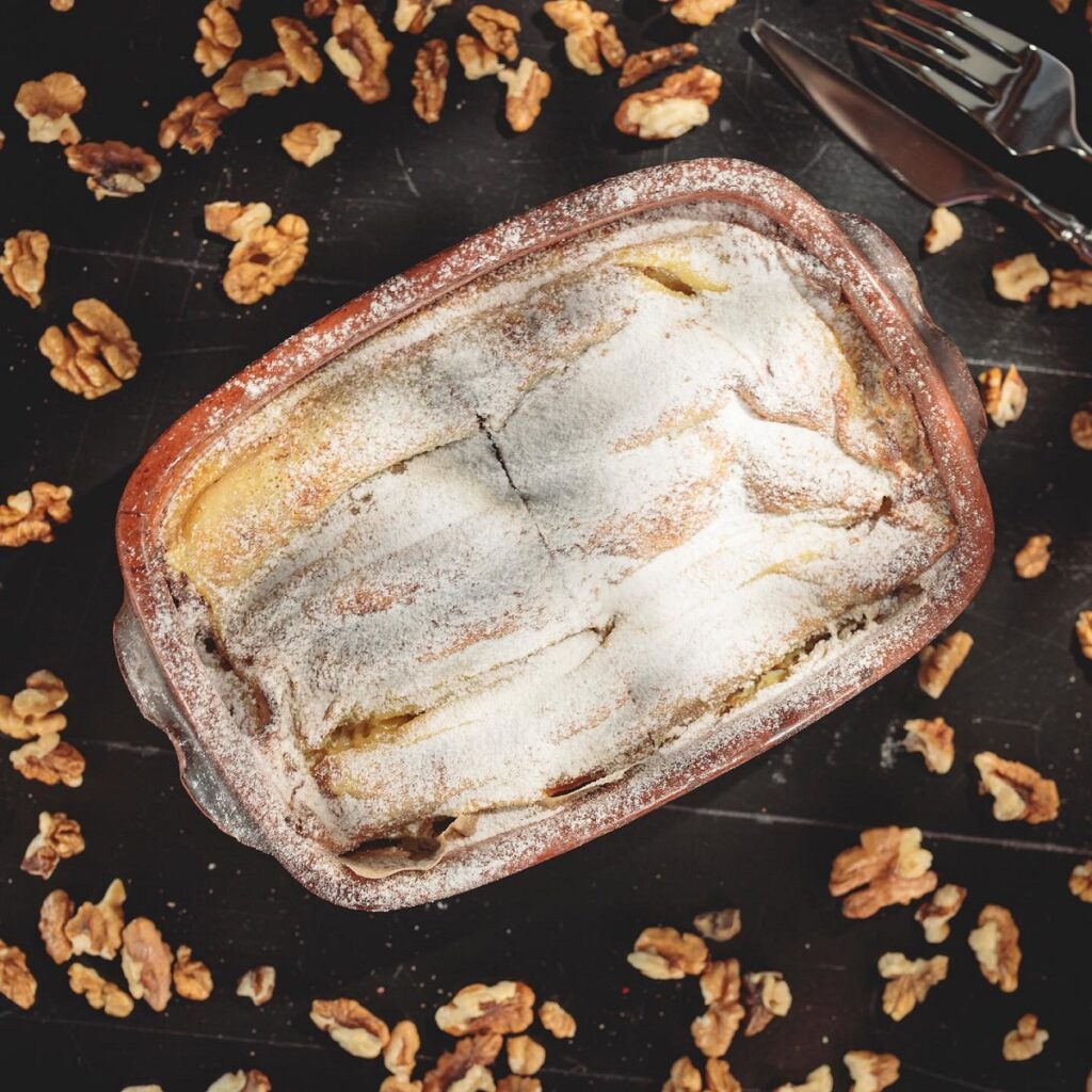 tava de lut cu placinta pudrata cu zahar, inconjurata de mieji de nuci, la Taverna Sarbului Sinaia,unul din cele mai bune restaurante de pe Valea Prahovei