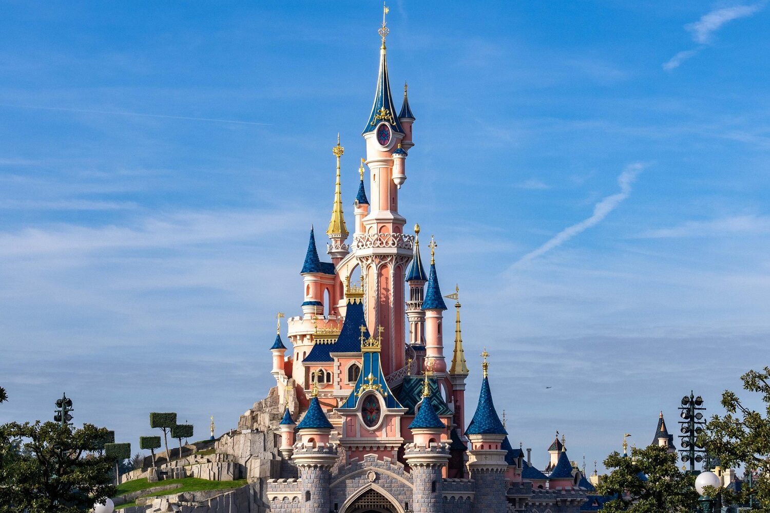 Castelul de la Disneyland Paris, cu turnuti inalte, ca din povești, pe fundalul unui cer albastru