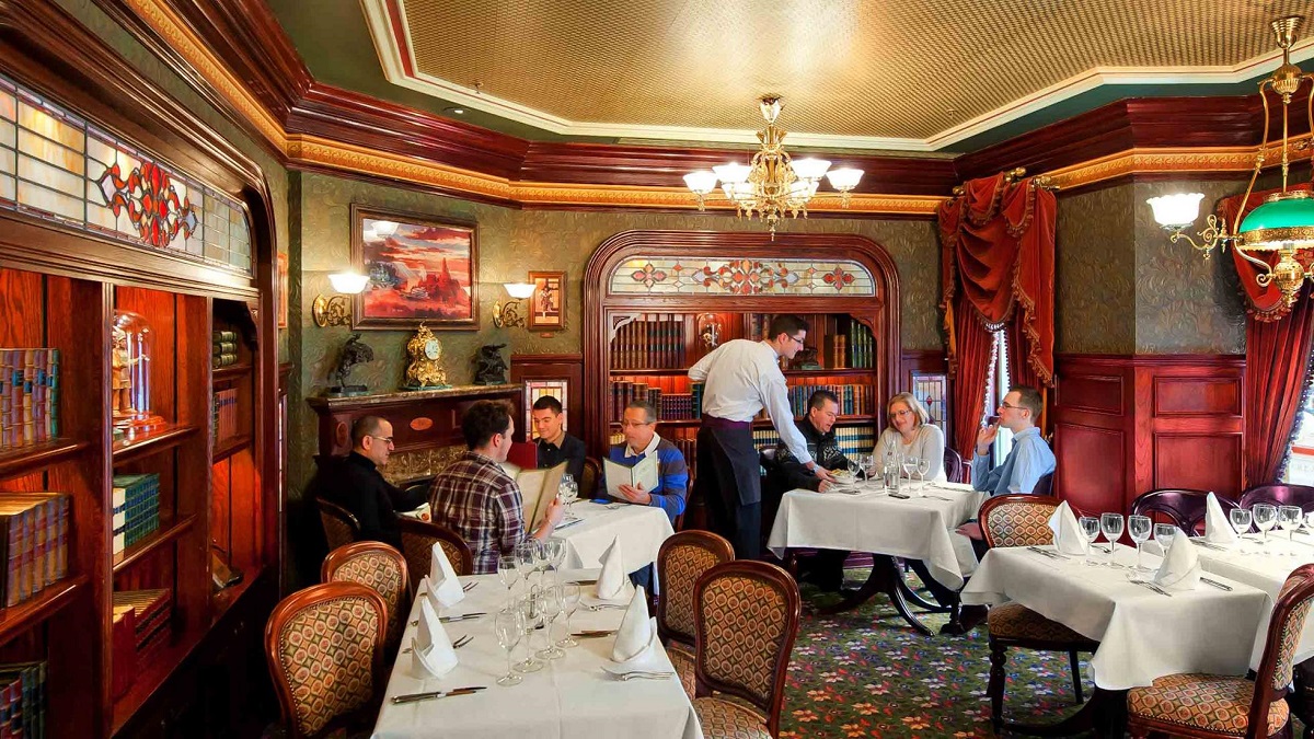 ospatar care serveste clienti la mese in restaurantul Walt's - an American Restaurant unde poți mânca într-o vizită la Disneyland Paris.