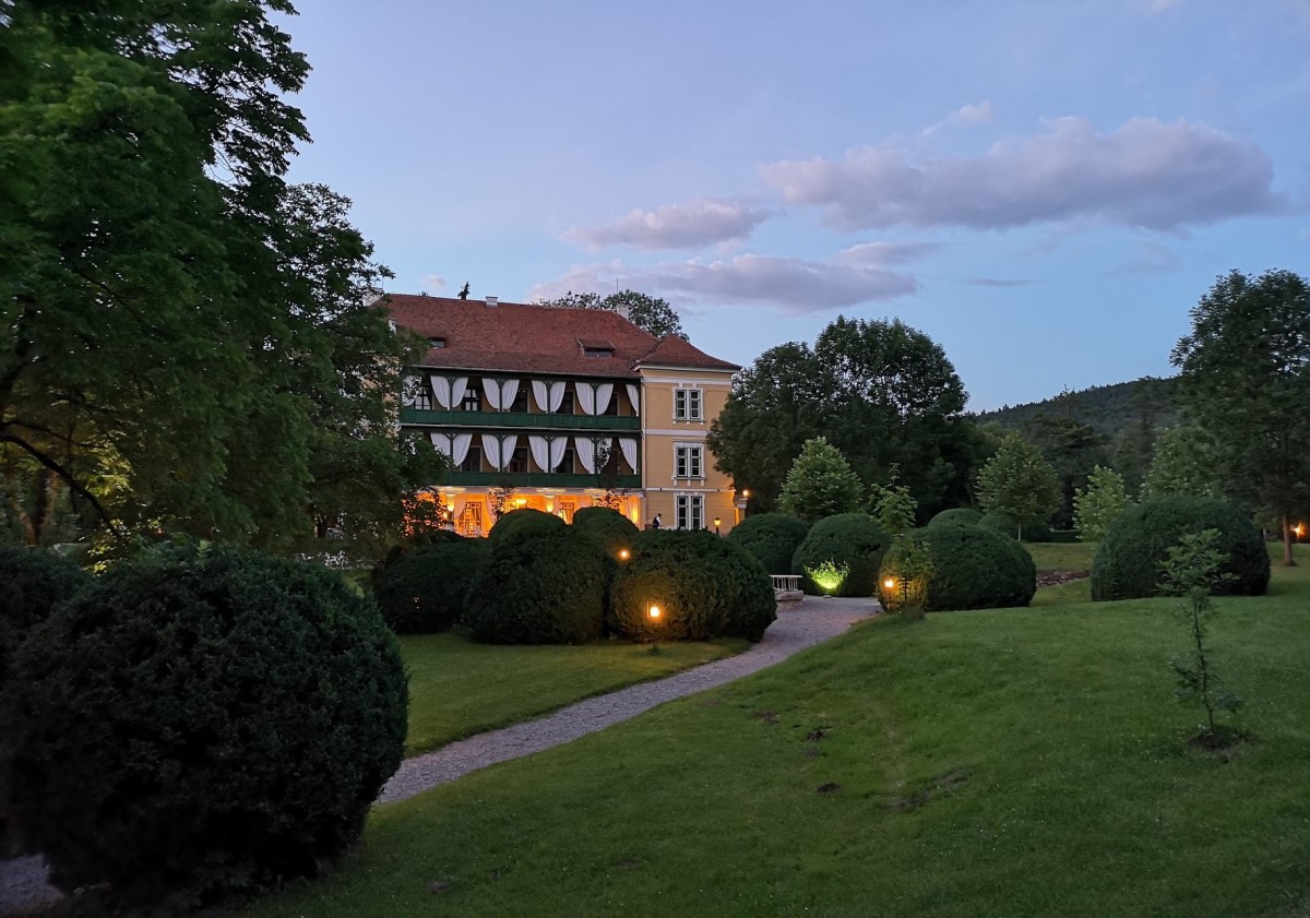 Cladirea principala de la Zabola Estate fotografiata in departare, pe inserat, cu o pajiste cu gazon verde in prim plan, una din destinații de tip retreat din România