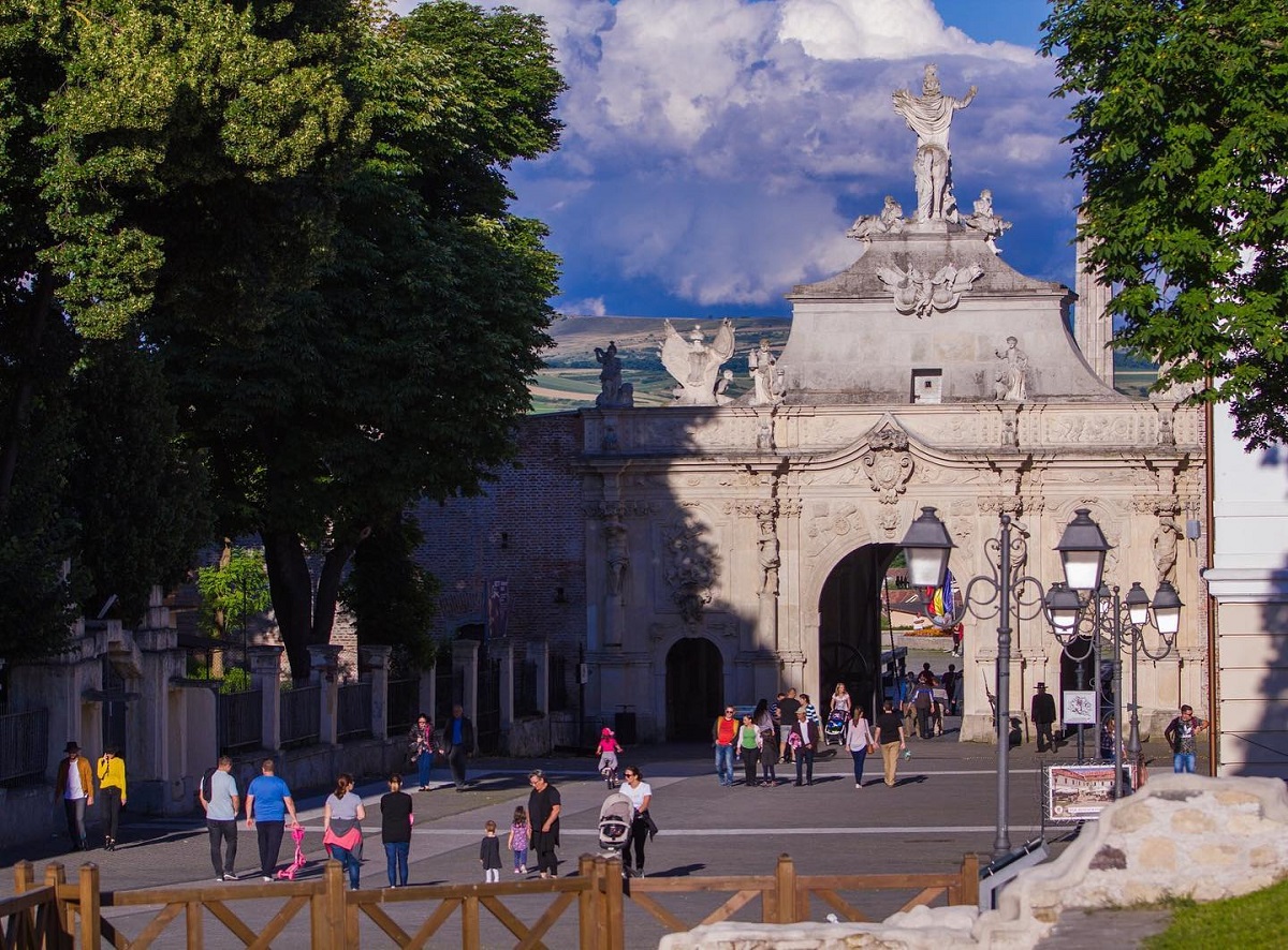 poarta principala din cetatea Alba Iulia, si alee in fata pe care se plimba oameni, un loc pe care sa-l vizitezi de 1 decembrie în România