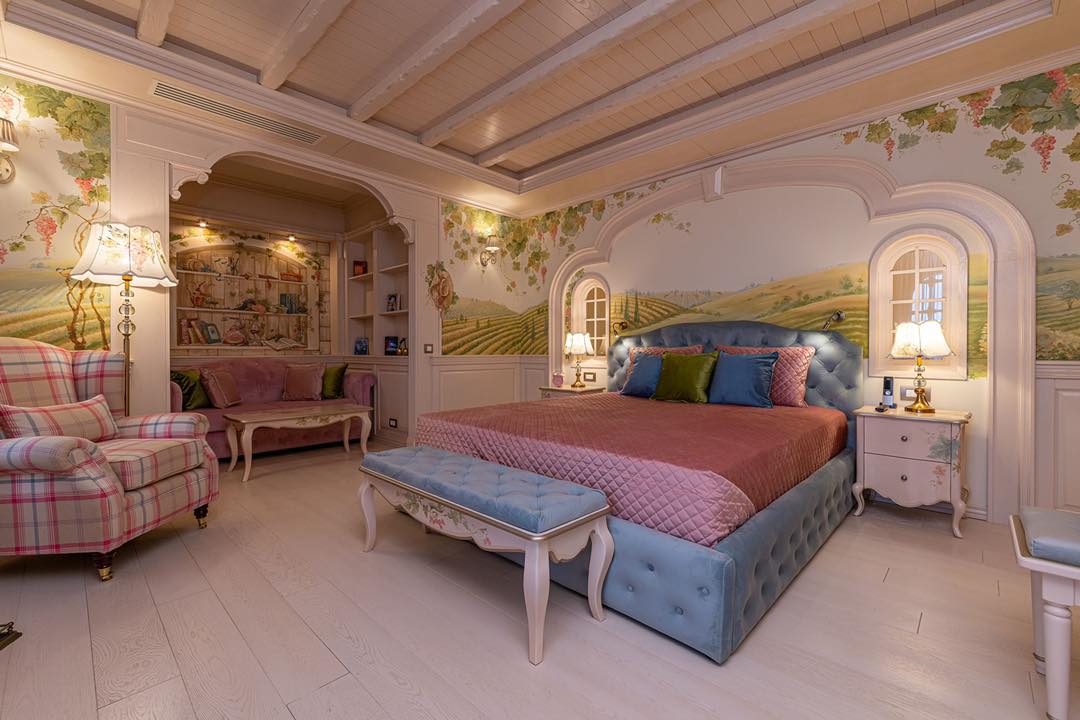 dormitor de la Casa Timiș, cu un pat mare, capitonat, mobilier in stil clasic si peretii pictati care amintesc de Toscana
