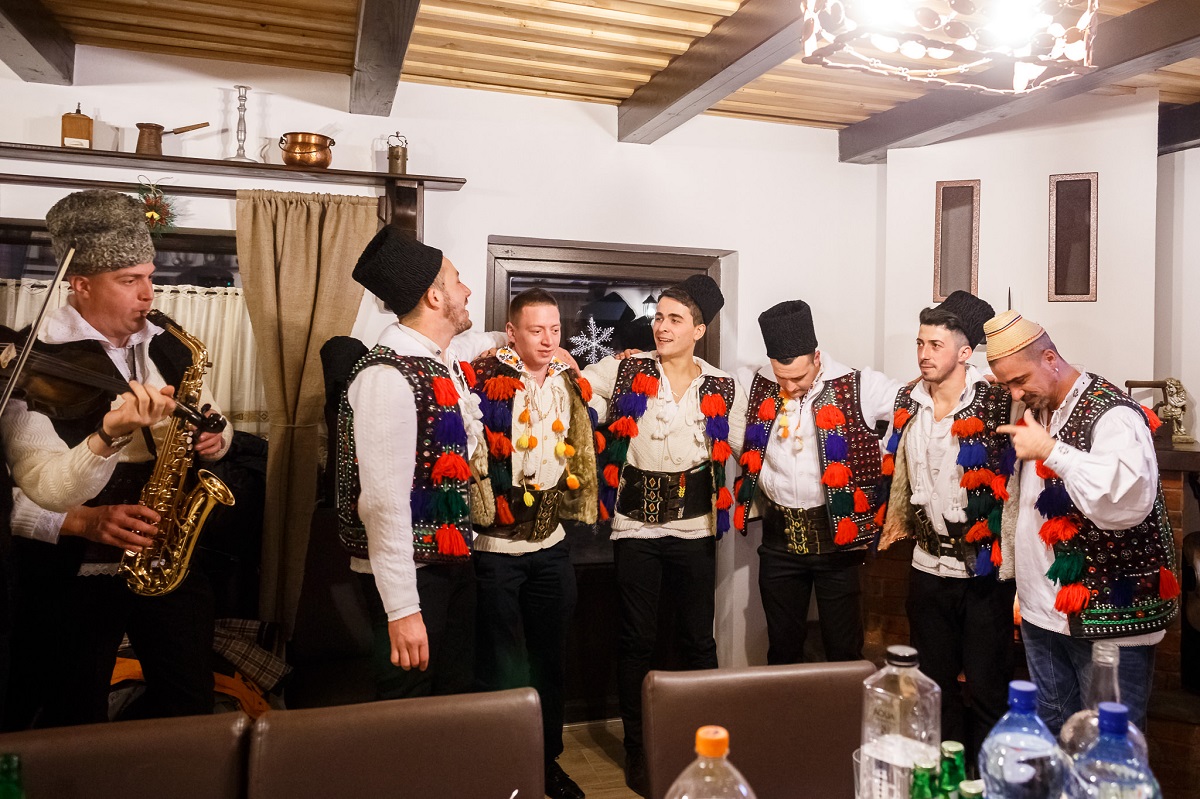 barbati imbracatai in costume populare maramureșene, la colindat in Casuta din Scobai