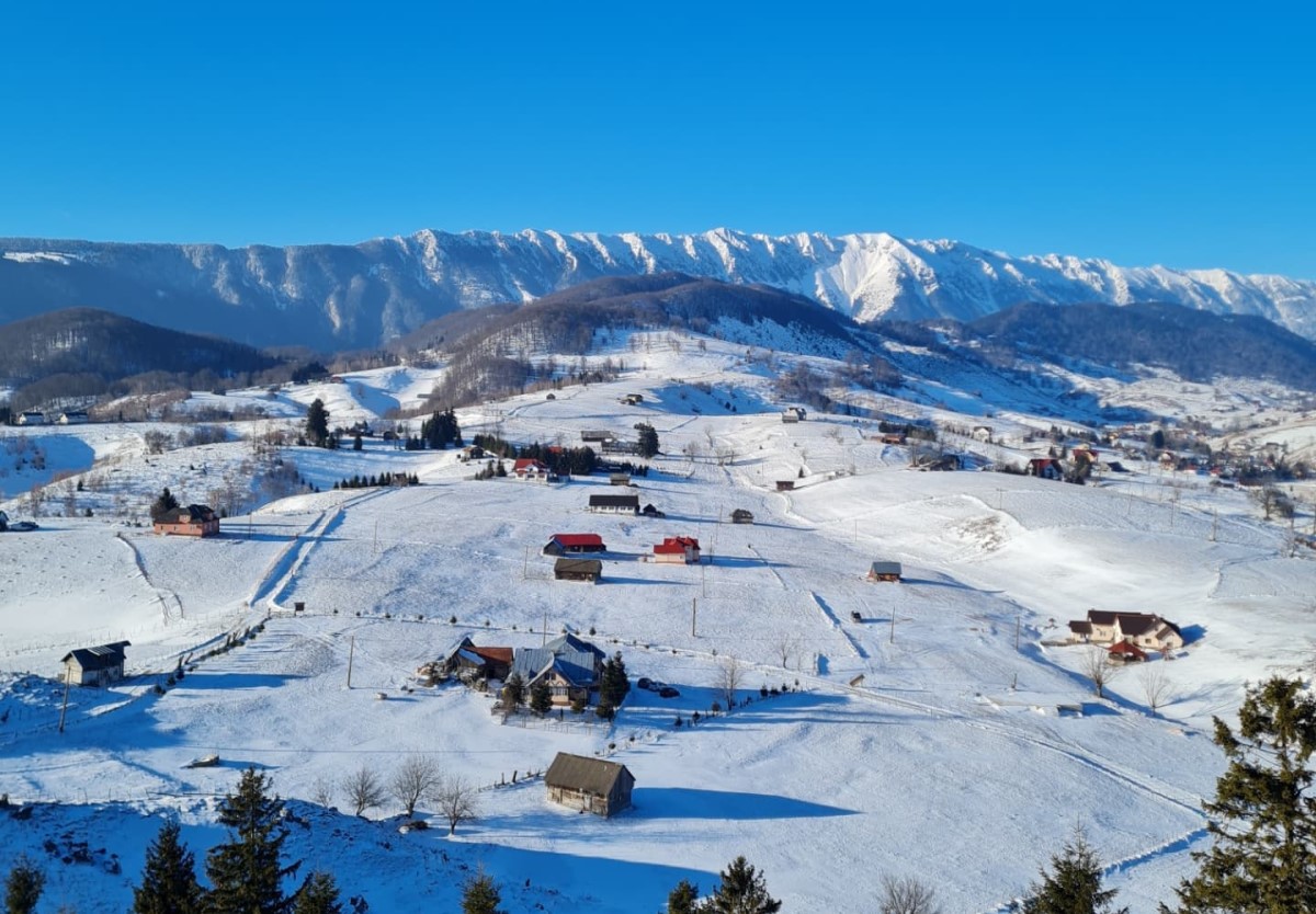 peisaj de iarna, cu muntii acoperiti de zapada si casute rasfirate pe deal, priveliste de la Ursa Mica asupra munților din Piatra Craiului
