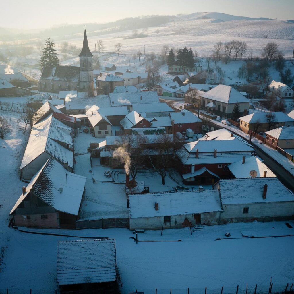 Satul de la Valea Verde fotografiat de sus, iarna, acoperit de zăpada, cu casute micute - destinație experiență de Crăciun