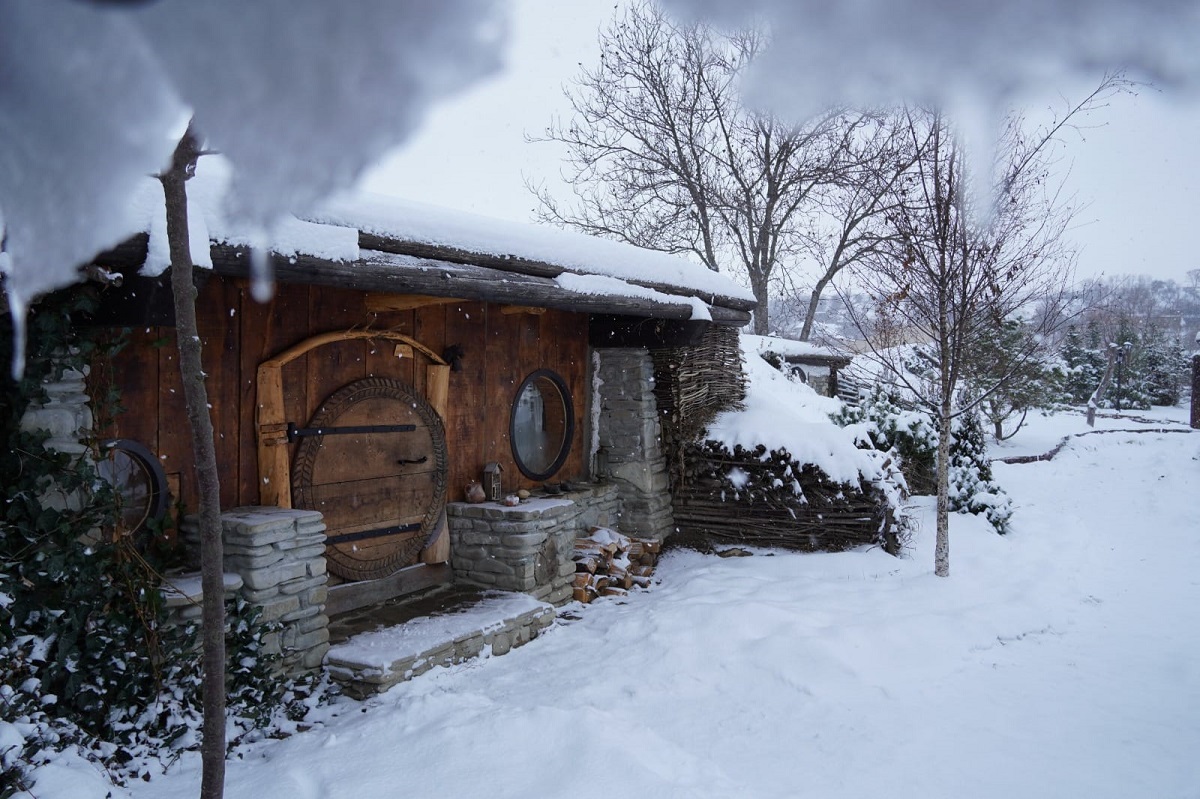 casuta mica, din lemn, de la Valea-celor-XII, fotografiata iarna cu curtea plina de zapada, una din destinații experiență pentru Crăciun