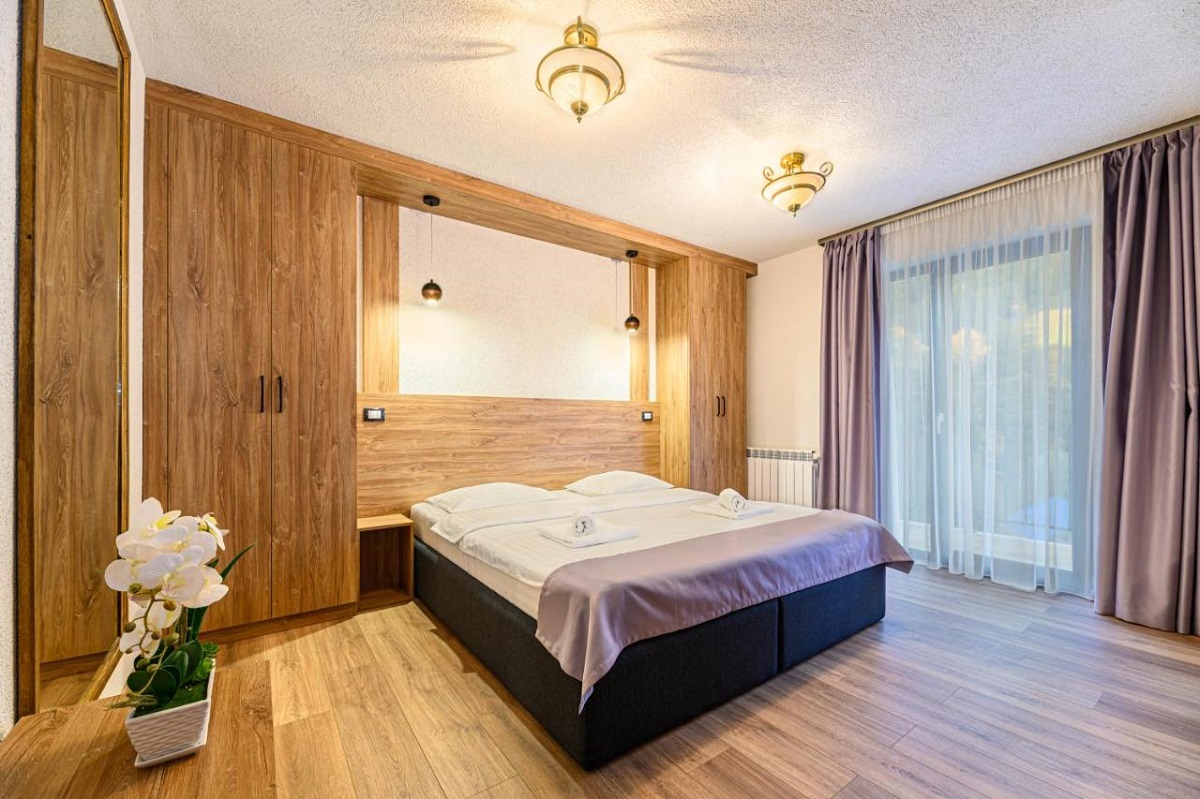 dormitor la Apuseni Wild, mobilat modern, cu un pat mare, pereti si parchet din lemn