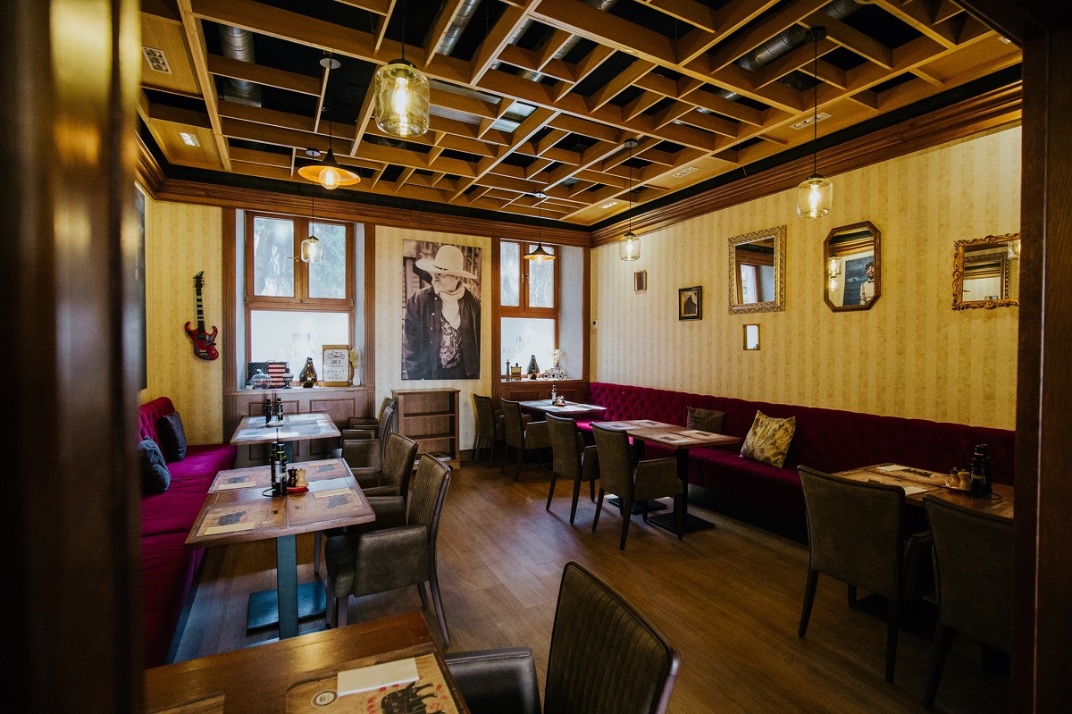 Benjamin Steakhouse din Sibiu, cu mese de o parte si de alta, iar in fundal cu ferestre si un tablou mare, unde sa iei masa in vacanta de 1 decembrie în România