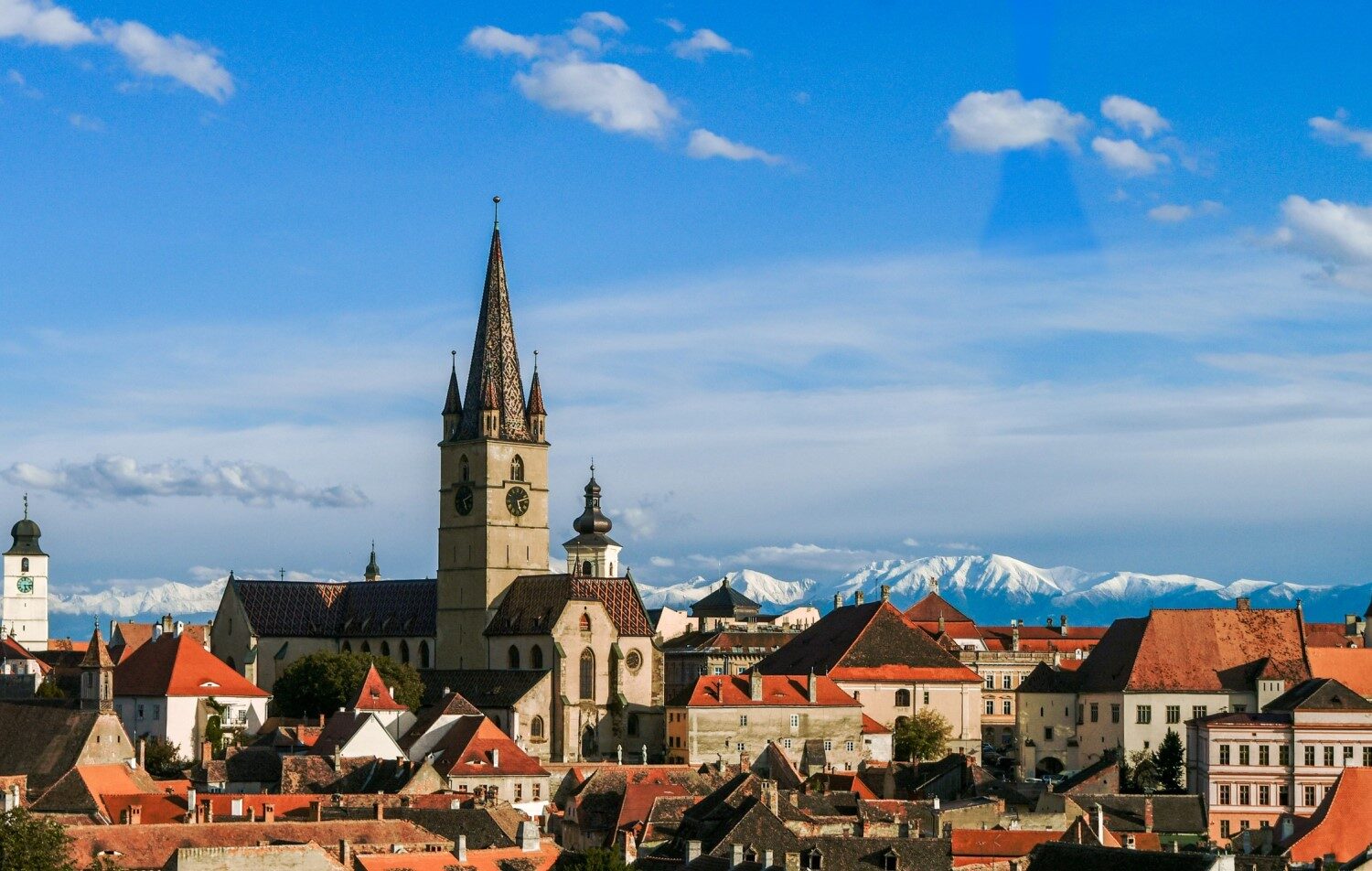 imagine de ansamblu asupra orașului Sibiu, cu turnul sfatului evidentiat si muntii inzapeziti in departare