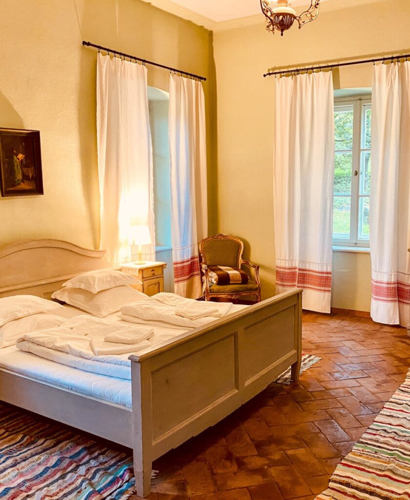 camera de cazare la conacul Apafi, cu un pat de 2 persoane si 2 ferestre mari, cu perdele, unde mergem de vacanța de 1 Decembrie