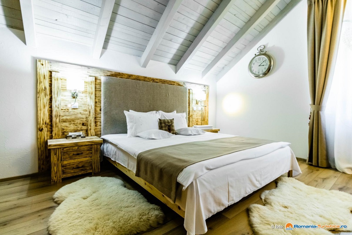 dormitor la mansarda, cu tavan alb din lemn, pat tapitat modern si lumini aprinse
