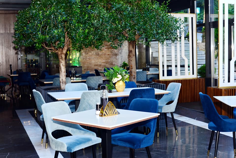 Restaurant noir din Predeal, elegant, cu mese de 4 persoane si scaune din catifea bleo si albastru, cu copaci in fundal