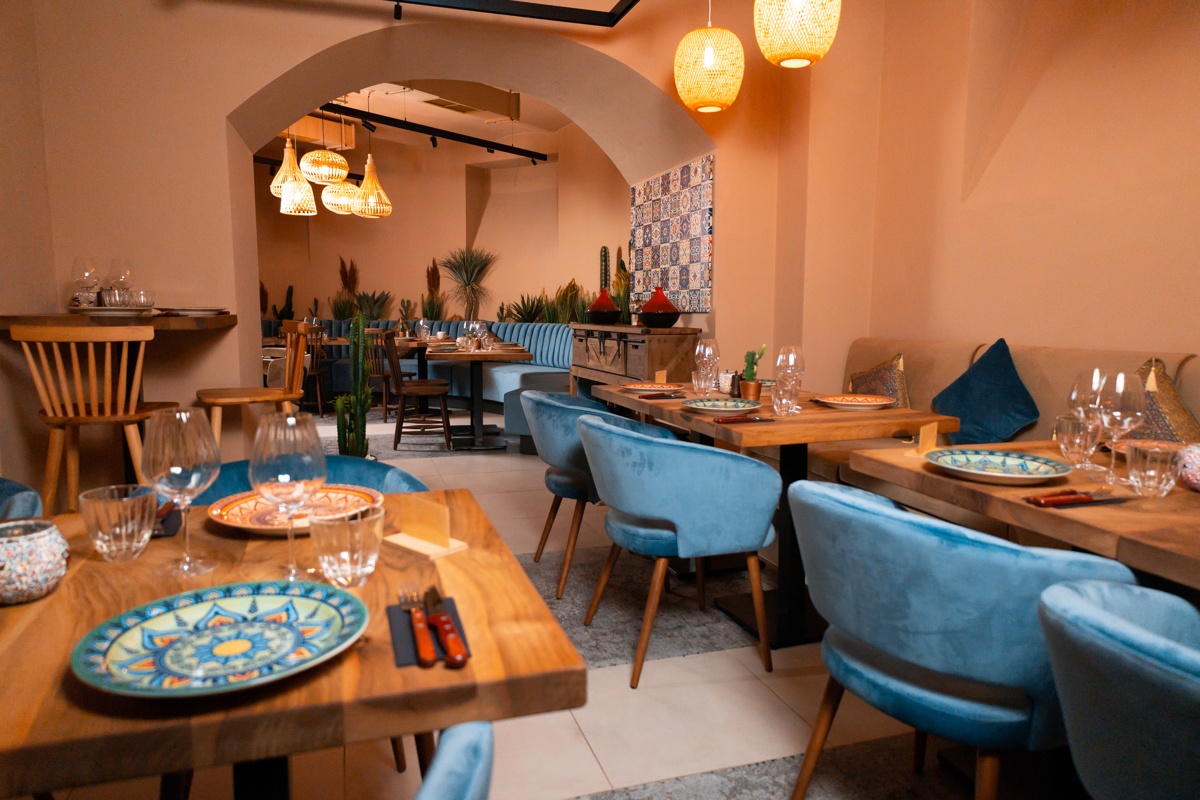 sala de evenimente de la restaurant Mace by Joseph Hadad, in culori calde si atmosfera intima, cu mese din lemn si scaune tapitate, albastre, restaurant potrivit pentru petrecerea de Crăciun a firmei